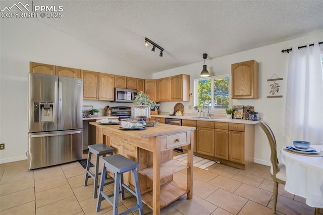 kitchen featuring a sink, appliances with stainless steel finishes, light tile patterned flooring, light countertops, and lofted ceiling