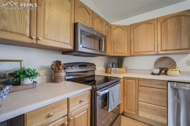 kitchen featuring a textured ceiling, light countertops, light tile patterned flooring, and stainless steel appliances