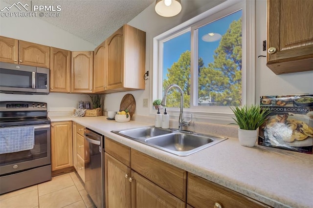 kitchen featuring a textured ceiling, light countertops, appliances with stainless steel finishes, and a sink