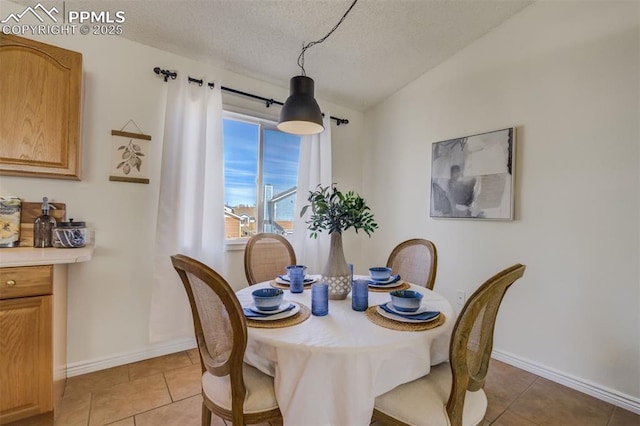 dining area with light tile patterned floors, a textured ceiling, and baseboards