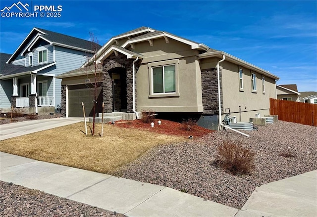 view of front of property with stucco siding, stone siding, driveway, and fence