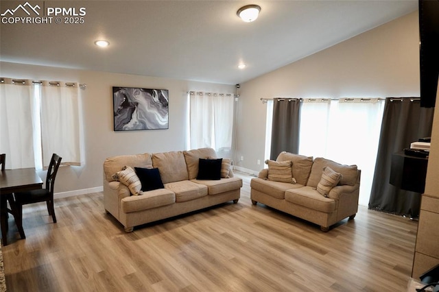 living area with baseboards, light wood-style flooring, and vaulted ceiling