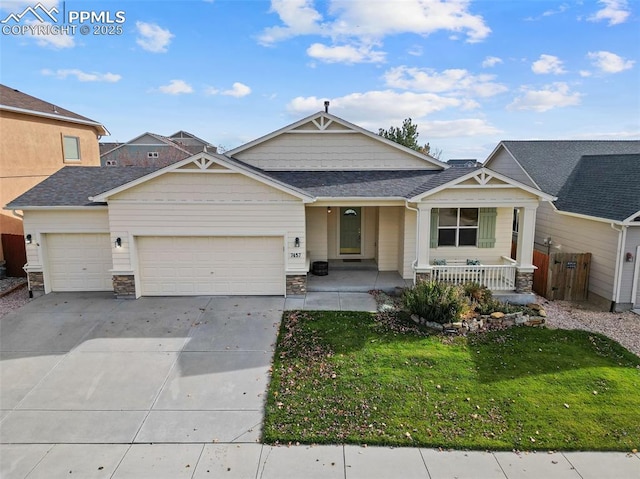 view of front of home with a front yard, driveway, roof with shingles, a porch, and a garage