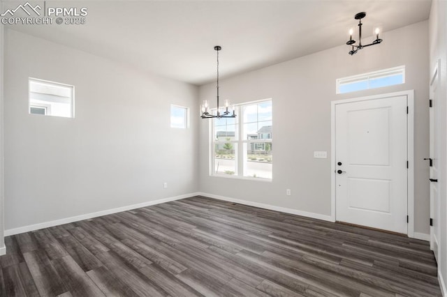 foyer featuring a notable chandelier, dark wood-style floors, and baseboards