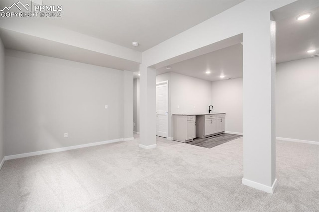 basement featuring recessed lighting, baseboards, light carpet, and a sink