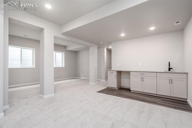 below grade area with visible vents, a sink, recessed lighting, carpet flooring, and baseboards