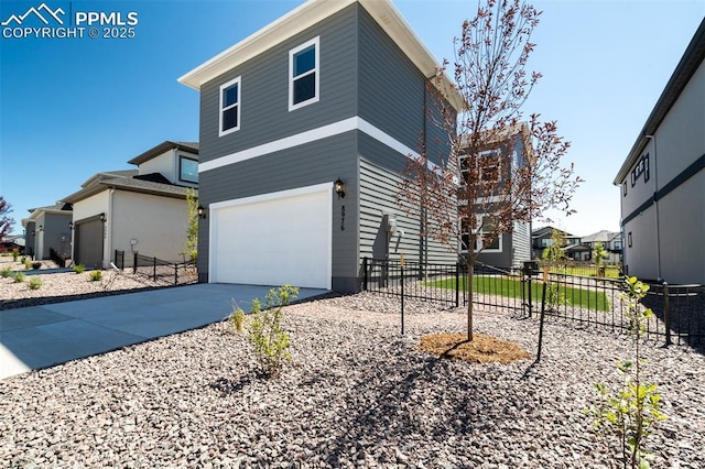 view of side of property with concrete driveway, an attached garage, and fence