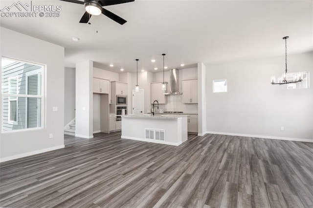 kitchen featuring visible vents, open floor plan, appliances with stainless steel finishes, wall chimney exhaust hood, and dark wood-style flooring