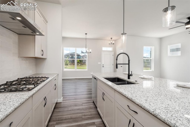 kitchen with dark wood-type flooring, under cabinet range hood, decorative backsplash, stainless steel appliances, and a sink