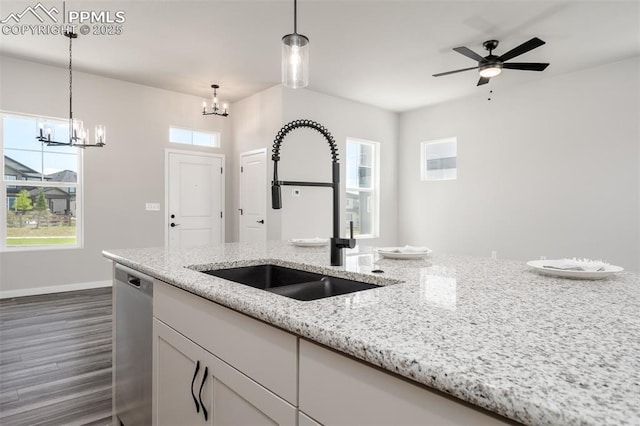 kitchen with stainless steel dishwasher, dark wood-type flooring, hanging light fixtures, and a sink