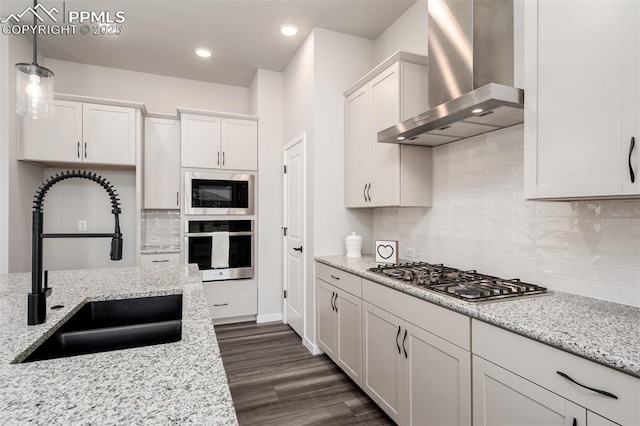 kitchen featuring a sink, tasteful backsplash, white cabinetry, stainless steel appliances, and wall chimney exhaust hood