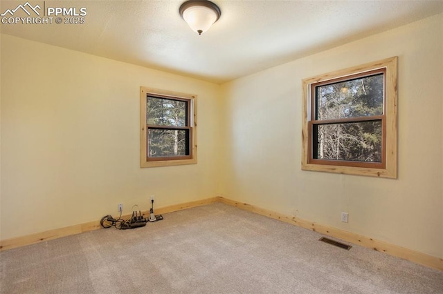 unfurnished room with visible vents, baseboards, and carpet flooring