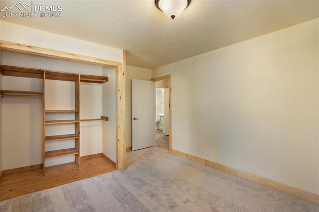 unfurnished bedroom featuring baseboards, a closet, carpet floors, and a textured ceiling