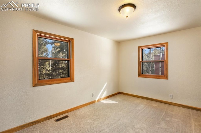 empty room with visible vents, carpet floors, and baseboards