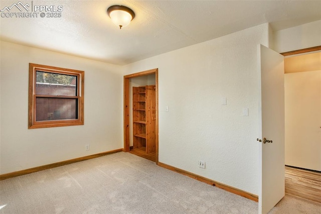 carpeted spare room featuring a textured wall, baseboards, and a textured ceiling