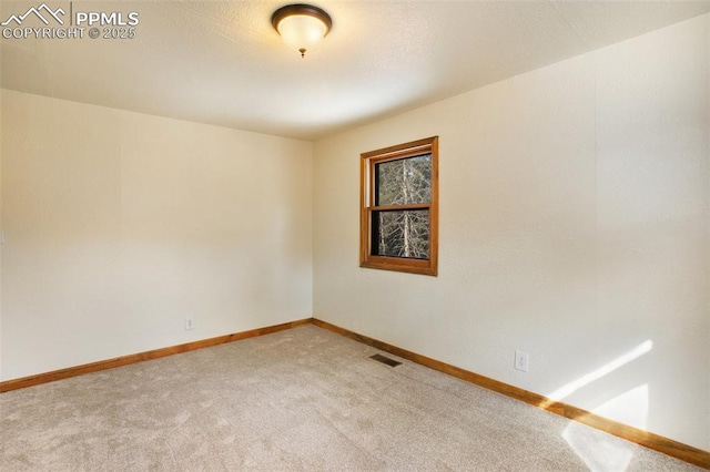 empty room featuring baseboards, visible vents, and carpet floors