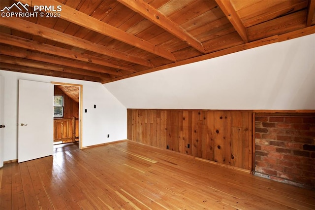 additional living space featuring hardwood / wood-style floors, wooden walls, vaulted ceiling with beams, and wood ceiling