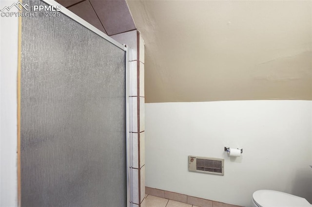 bathroom featuring tile patterned floors, heating unit, toilet, and a stall shower