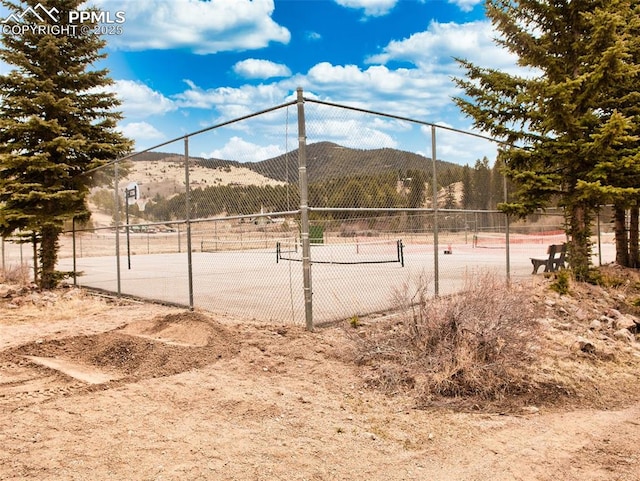 surrounding community with a tennis court, fence, and a mountain view