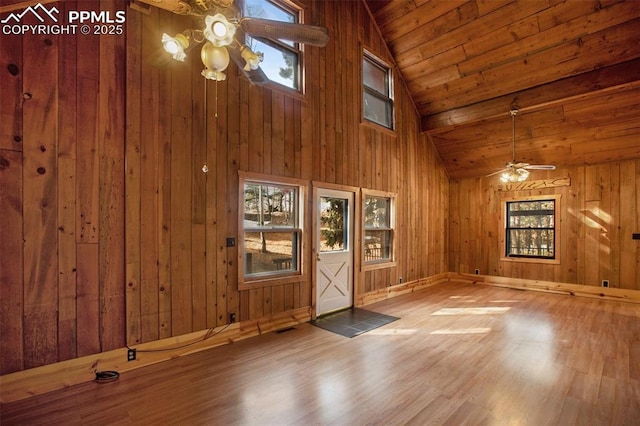 empty room with wood walls, wooden ceiling, ceiling fan, and wood finished floors