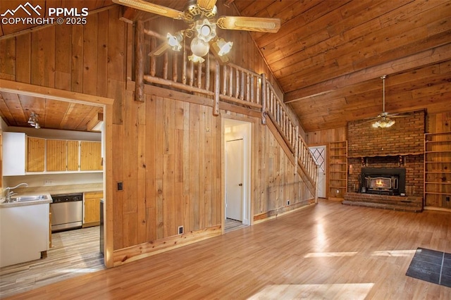 unfurnished living room featuring wooden walls, ceiling fan, light wood-style flooring, wooden ceiling, and a sink