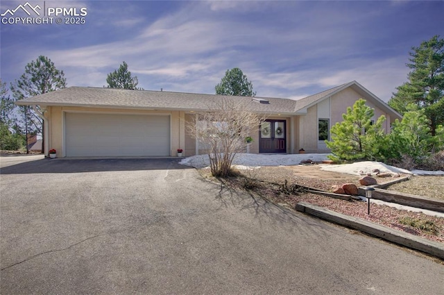 view of front of home with stucco siding, an attached garage, and driveway