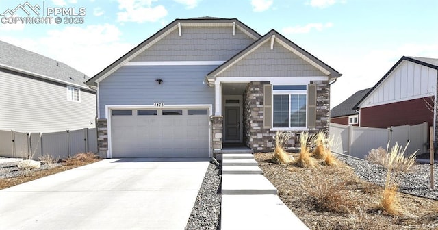 craftsman-style home featuring a garage, fence, stone siding, and driveway