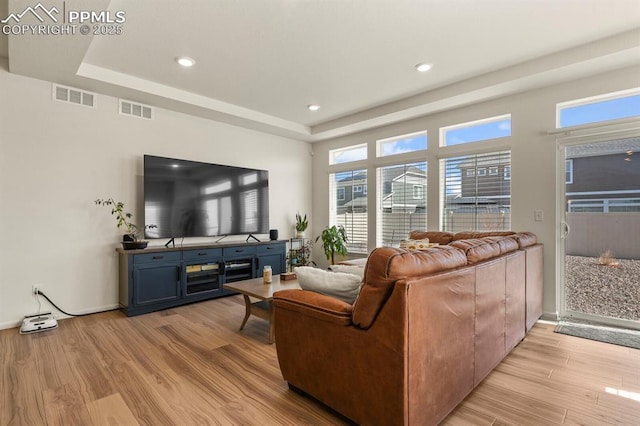 4478 Riviera Ct, Aurora, CO 80019 - living room with visible vents, light wood-style flooring, and a tray ceiling