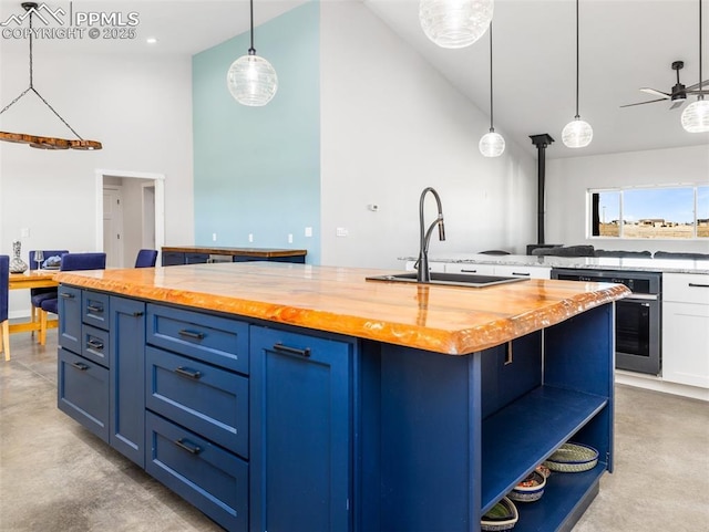 kitchen featuring blue cabinets, wooden counters, concrete flooring, and a sink