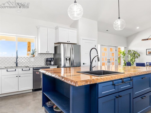 kitchen with concrete floors, a sink, decorative backsplash, stainless steel appliances, and white cabinets