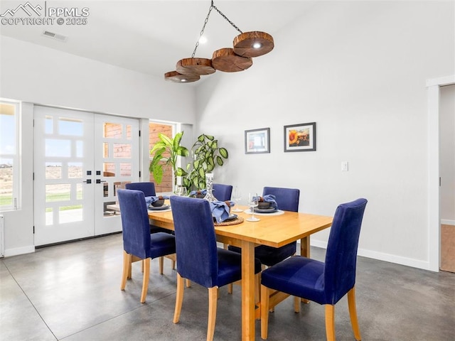 dining space with visible vents, finished concrete flooring, baseboards, french doors, and a high ceiling