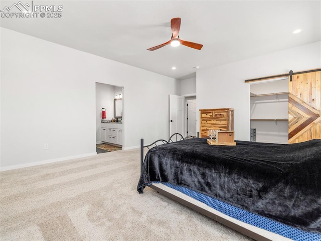 carpeted bedroom with a ceiling fan, ensuite bath, recessed lighting, a barn door, and baseboards