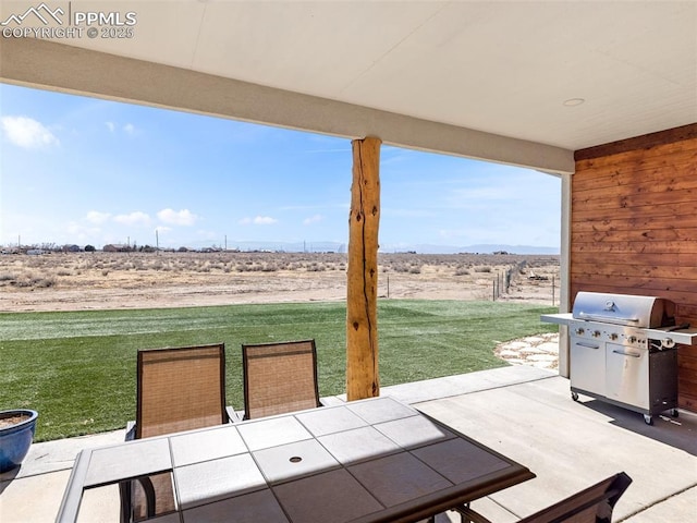 view of patio featuring outdoor dining space, a rural view, and a grill