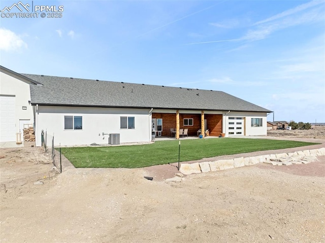 rear view of property with roof with shingles, stucco siding, cooling unit, a yard, and a patio area