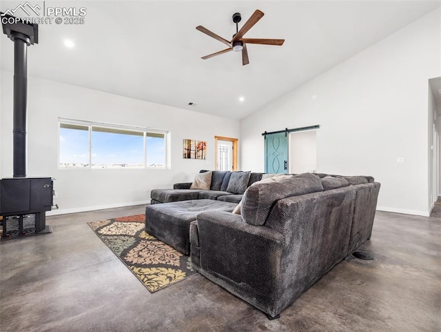 living area with a barn door, a wood stove, finished concrete flooring, and baseboards