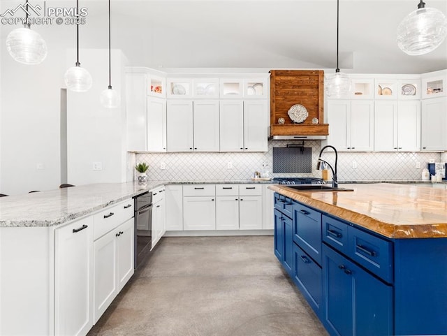 kitchen with a sink, blue cabinets, tasteful backsplash, and a peninsula