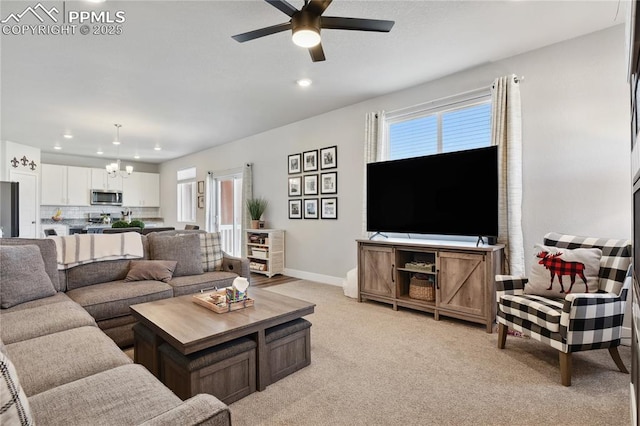 living room with light carpet, recessed lighting, ceiling fan with notable chandelier, and baseboards