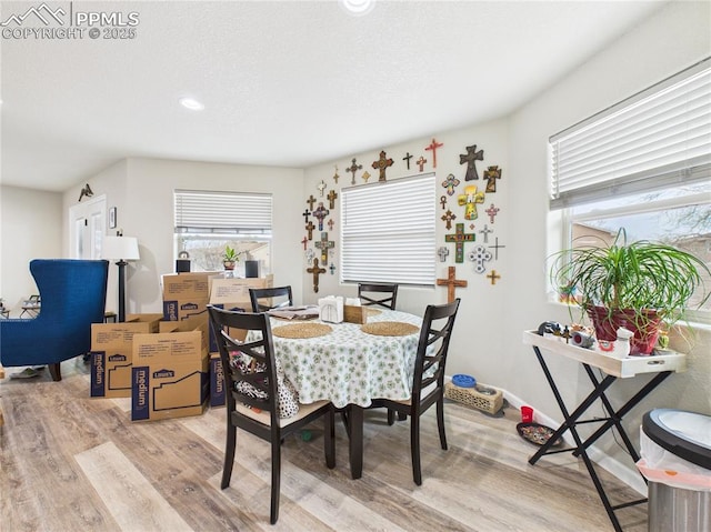 dining space featuring light wood-style flooring, recessed lighting, and a textured ceiling