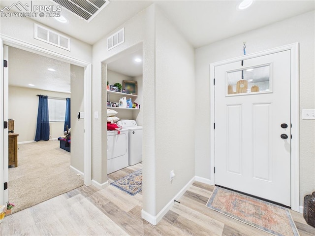 entrance foyer featuring visible vents, washing machine and dryer, and light wood-style floors