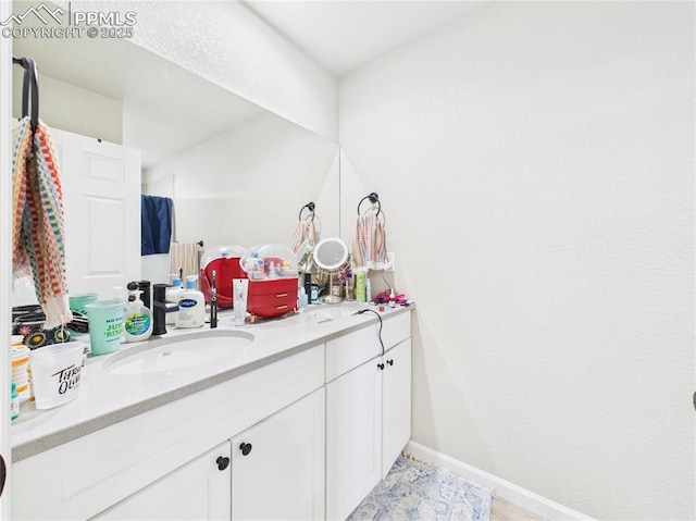 full bathroom featuring double vanity, baseboards, and a sink