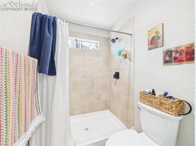 bathroom featuring toilet, a textured wall, and a tile shower