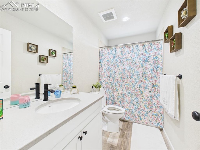 bathroom featuring visible vents, toilet, a shower with shower curtain, wood finished floors, and vanity