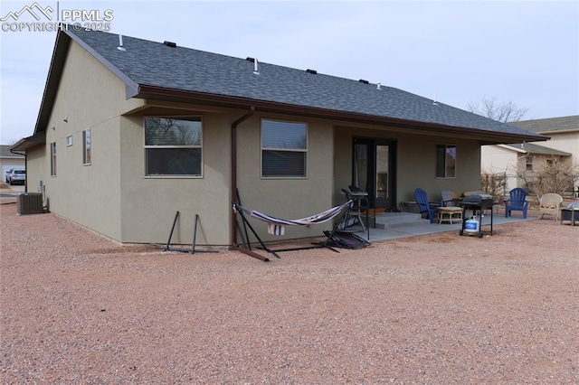 rear view of property with a patio, stucco siding, central AC unit, and a shingled roof