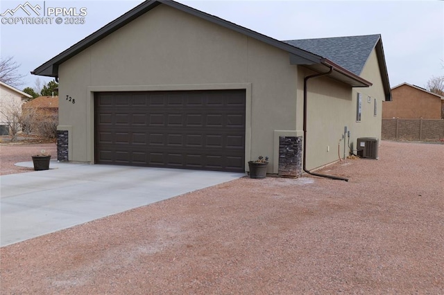 view of side of property featuring concrete driveway, cooling unit, a garage, and stucco siding