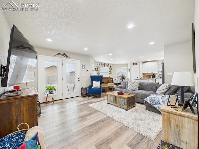 living room featuring recessed lighting, light wood-style flooring, and a textured ceiling