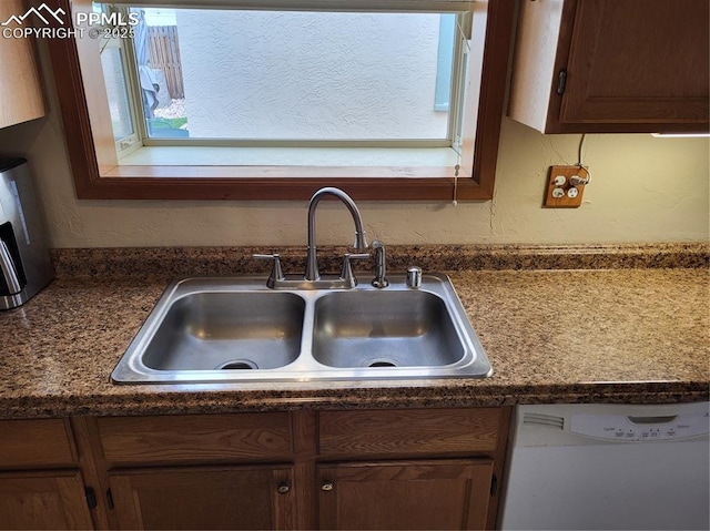 kitchen with a sink, dark countertops, and dishwasher