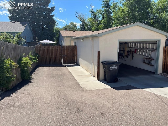 view of side of home with a gate, stucco siding, a garage, and fence