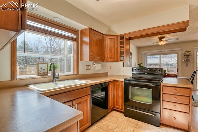 kitchen featuring black appliances, light countertops, a sink, and a peninsula
