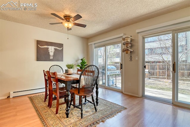 dining area featuring baseboard heating, baseboards, a textured ceiling, ceiling fan, and wood finished floors