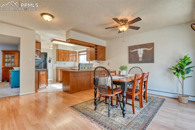dining room with light wood-type flooring, ceiling fan, a baseboard heating unit, and a textured ceiling